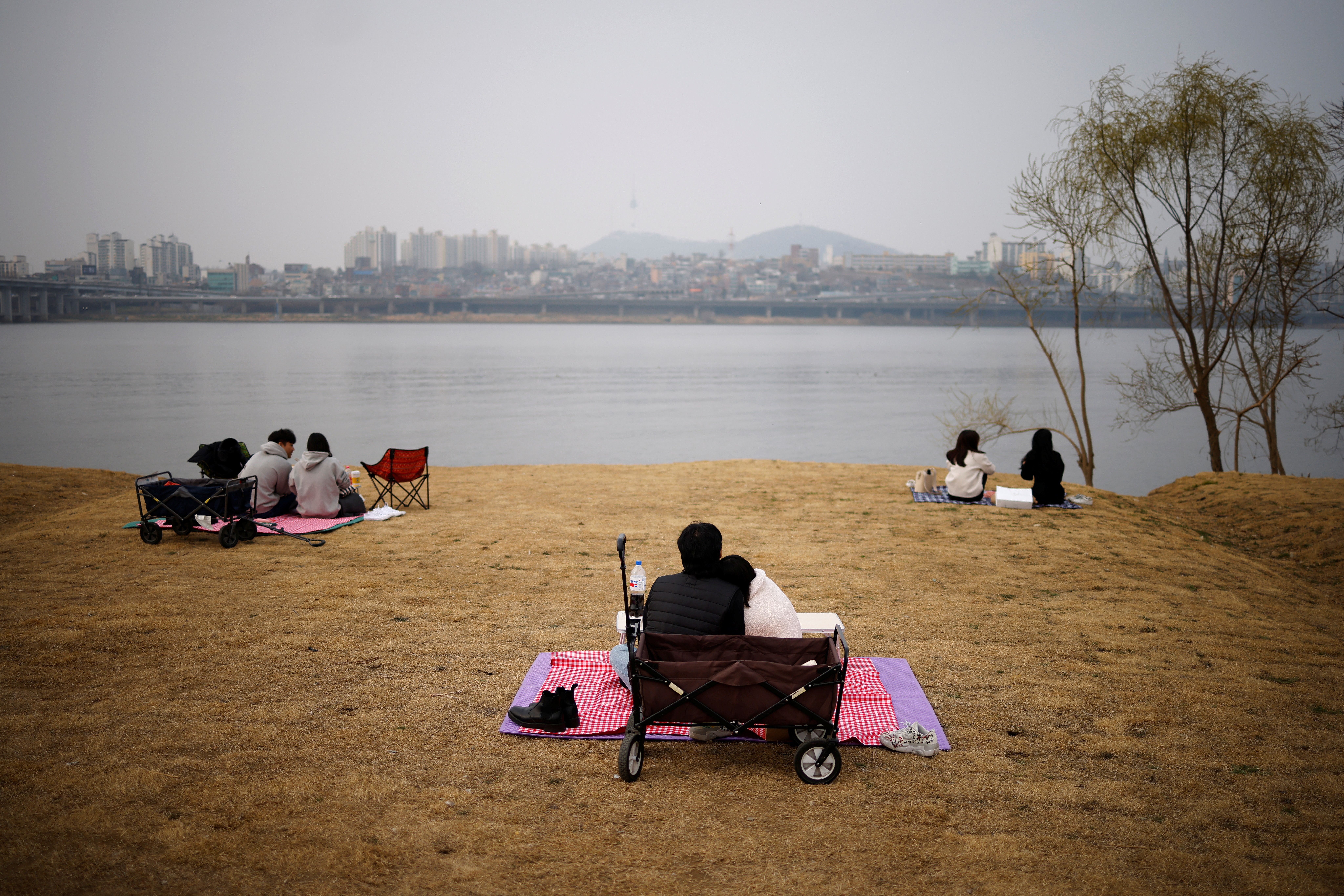 ▲▼首爾15日天空開始受蒙古沙塵暴影響，民眾戴著口罩在漢江公園野餐（圖／路透社）