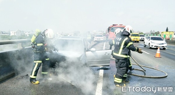 ▲1輛行駛國道2號桃園路段的轎車26日上午突然引擎冒火，轎車隨即陷入大火，消防人員現場灌救。（圖／記者沈繼昌翻攝）