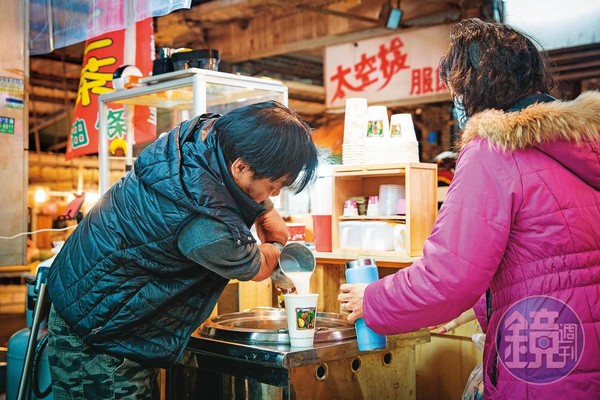 林建民（左）雖然截肢，但用鋼杯舀杏仁湯、裝杯都難不倒他。