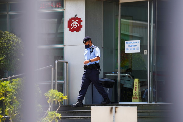 ▲員警從香港蘋果日報大樓走出，門上貼有臨時關閉的公告。（圖／路透）