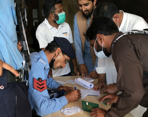 ▲▼巴基斯坦首都伊斯蘭馬巴德（Islamabad）的大型疫苗接種中心，一名警察正在幫助移工填寫表格，以便前往國外工作。（圖／路透）