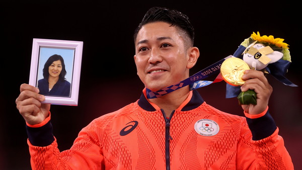 日本空手道選手喜友名諒在決賽中奪金，他拿著母親遺照、淚灑頒獎台。（圖／路透）