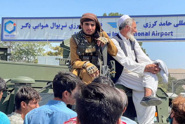 ▲▼阿富汗喀布爾哈米德卡爾扎伊國際機場外，一名塔利班部隊成員（左）坐在一輛裝甲車上。（圖／路透）