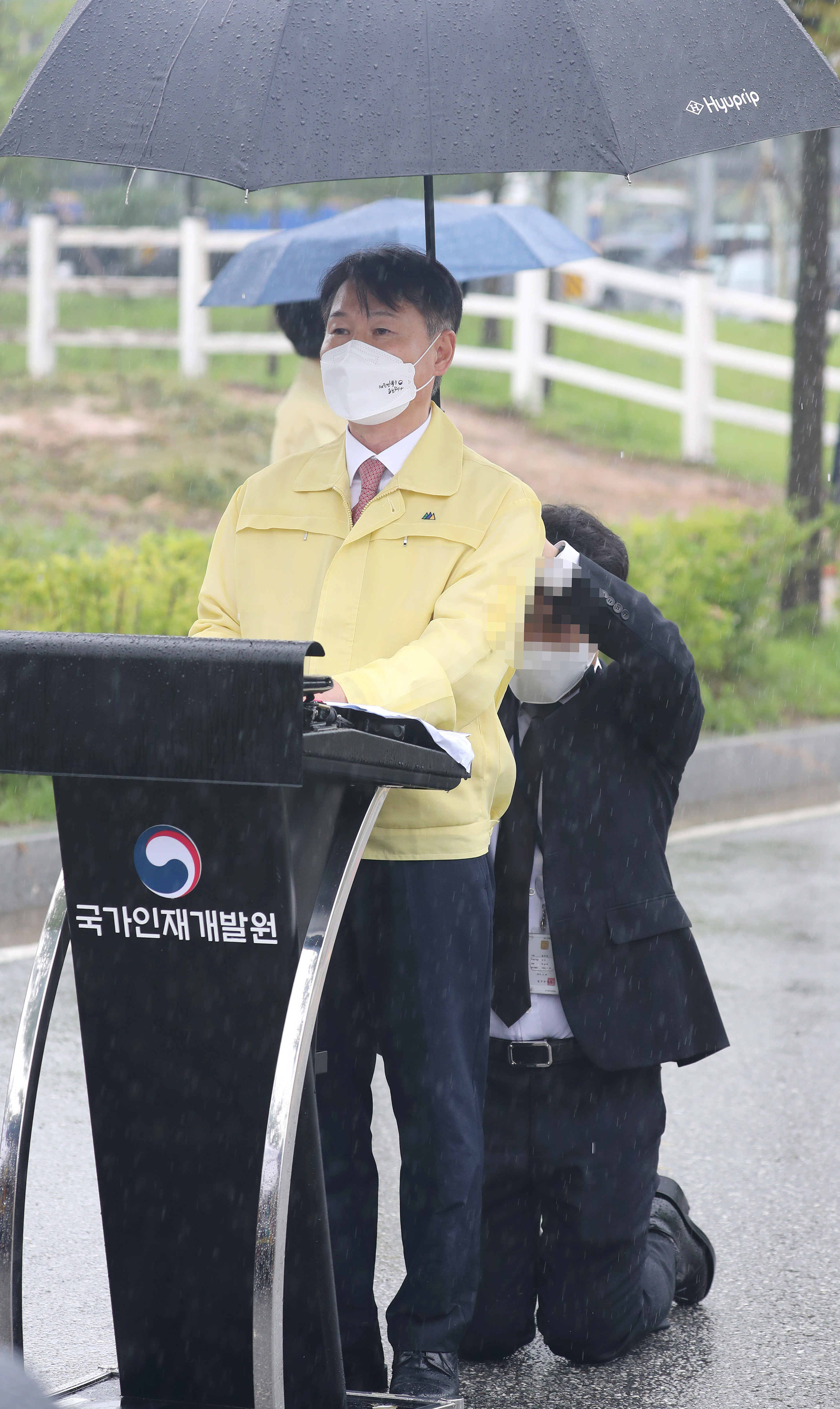 ▲▼南韓法務部次長姜聲國發表談話，秘書雨中跪地撐傘。（圖／達志影像）