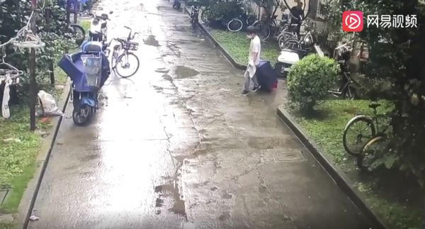 ▲上海一名年輕女子在租屋處遇害，社區監視器拍下犯嫌拖行李箱從居民樓門口走出。（圖／翻攝上游新聞）
