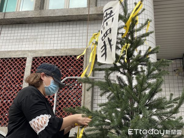 ▲▼司改會與羅明村女兒在新莊分局前辦聲援會，要提非常上訴「還羅明村清白人生」，女兒在樹上繫上黃絲帶，分局督察組長收下案情摘要錦囊             。（圖／記者陳以昇攝）