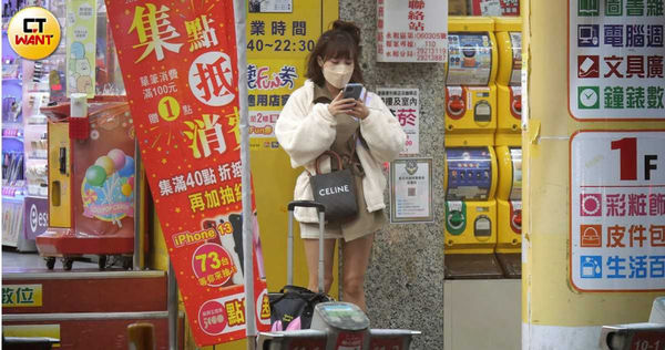 穿著熱褲的孟潔站在店門口邊看手機訊息邊四處張望，似乎在等人。（圖／本刊攝影組）