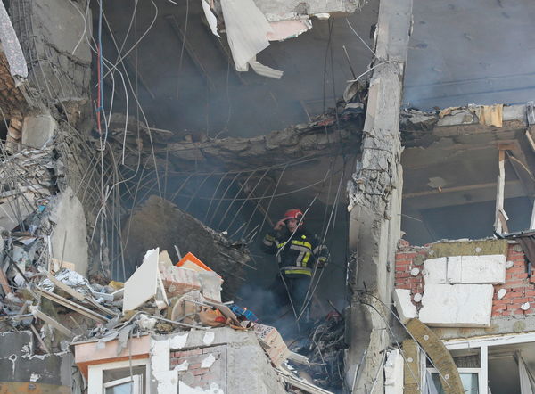 ▲▼烏克蘭基輔26日上午一棟住宅大樓遭俄軍導彈轟炸，建物外牆遭炸出一個大洞，消防人員緊急滅火與搜救，現場還出現沾有血跡的襯衫。（圖／路透）
