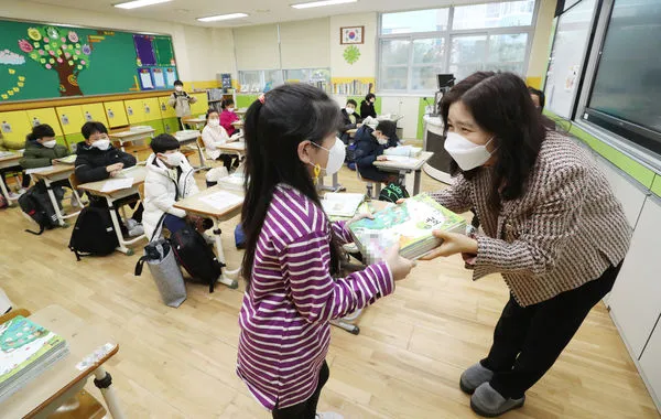 ▲▼ 南韓一名小學教師發課本給學生。。（圖／達志影像）