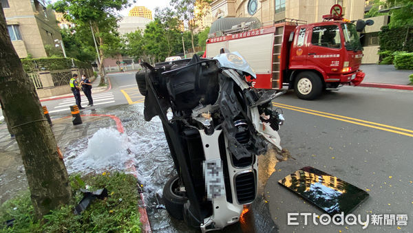 ▲信義區一名女駕駛自撞路邊消防栓，BMW側翻車頭全毀。（圖／記者游宗樺攝）