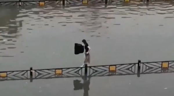 ▲河南洛陽暴雨，女子走在道路護欄上秀極佳平衡感。（圖／翻攝微博）