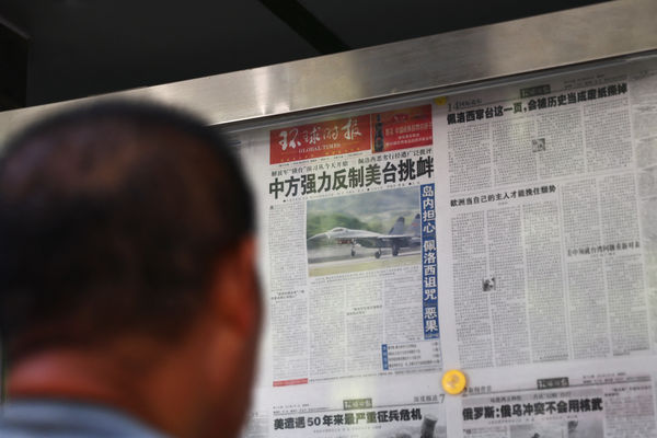 ▲▼北京男子閱讀《環球時報》關於解放軍在台灣附近舉行軍事演習的報導。（圖／路透）