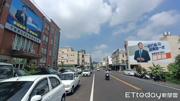 ▲▼國民黨苗栗縣黨部對面的建築物外牆掛著鍾東錦的巨型看板，與謝福弘在縣黨部的看板「互別苗頭」，凸顯目前苗栗藍營分裂的緊繃態勢。（圖／記者蔡文淵攝）