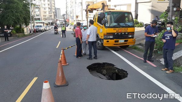 ▲台南市永康區新行街下午路面突出現塌陷，出現1公尺寛的大坑洞，1部轎車車輪陷入坑洞內動彈不得，員警到場交通管制疏導，並通知區公所派員處置。（圖／民眾提供，下同）