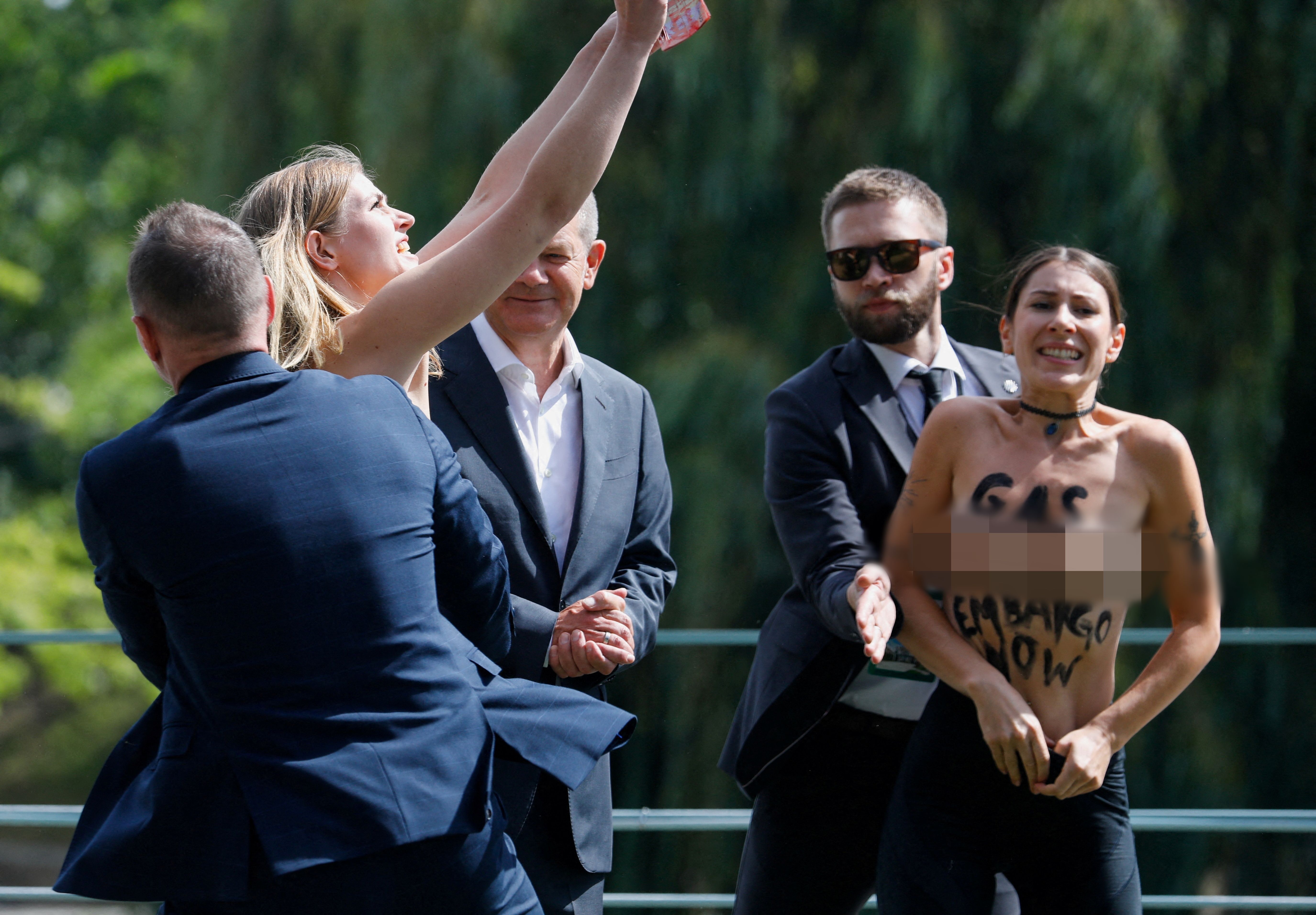 ▲▼2名女子在德國總理蕭茲（Olaf Scholz）面前脫上衣裸身抗議。（圖／路透）