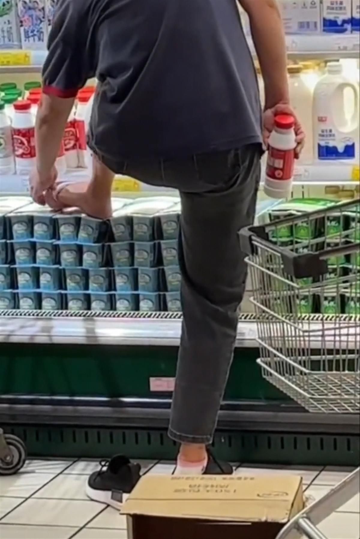▲▼超市導購員脫襪踩在冰櫃酸奶上敷腳。（圖／翻攝自極目新聞）