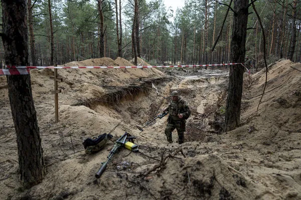 ▲▼烏克蘭軍人使用金屬探測器檢查伊久姆（Izium）一處萬人坑。（圖／達志影像／美聯社）