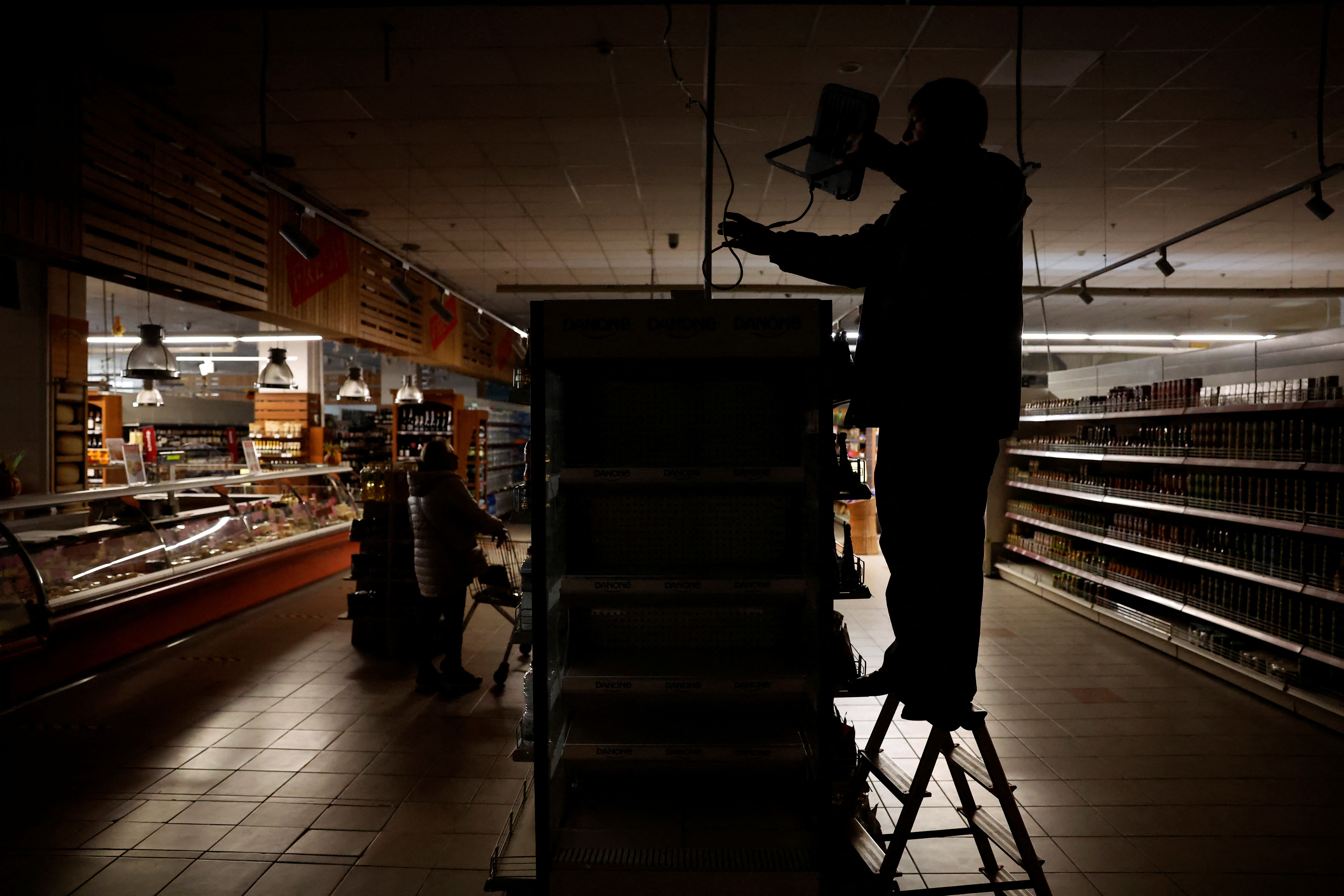 ▲▼烏克蘭哈爾科夫因俄軍導彈襲擊而遭遇停電，民眾摸黑在超市內購物。（圖／路透）