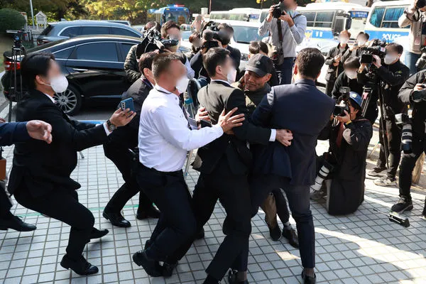 ▲▼公務員李大俊的胞兄李萊晉21日前往首爾中央地方法院向徐旭提出抗議，遭警衛包圍。（圖／達志影像／newscom）
