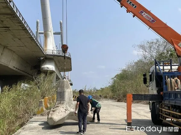 ▲▼水利署第二河川局吊來消波塊，阻擋苗栗縣客屬大橋下方後龍溪河床道路，防止繼續遭亂倒。（圖／記者蔡文淵翻攝）