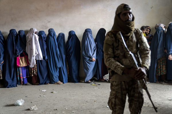 ▲▼阿富汗女性2023年5月23日排隊等待領取人道主義援助組織發送的糧食，一名塔利班武裝人員站崗。（圖／達志影像／美聯社）