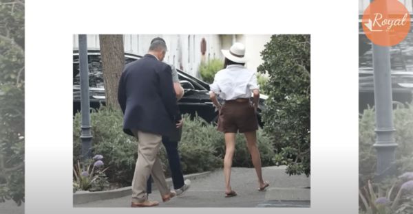 梅根身穿白色Anine Bing襯衫、搭配Reformation棕色亞麻短褲，露出一雙纖細長腿，腳上的涼鞋來自Hermes。（翻攝Royal Reels YouTube頻道）