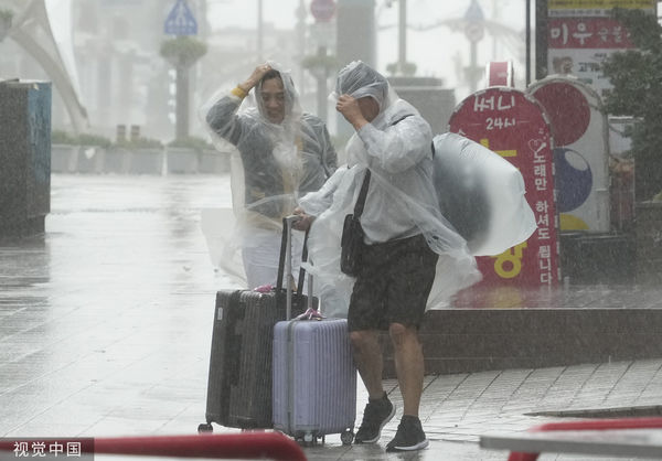 ▲▼卡努颱風襲南韓，釜山海邊出現大浪，民眾穿雨衣抵抗風雨。（圖／CFP）