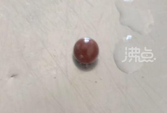 ▲吉林一名女子在市場買到的河蚌中發現一顆晶瑩剔透的暗紅色小珍珠。（圖／翻攝沸點視頻）