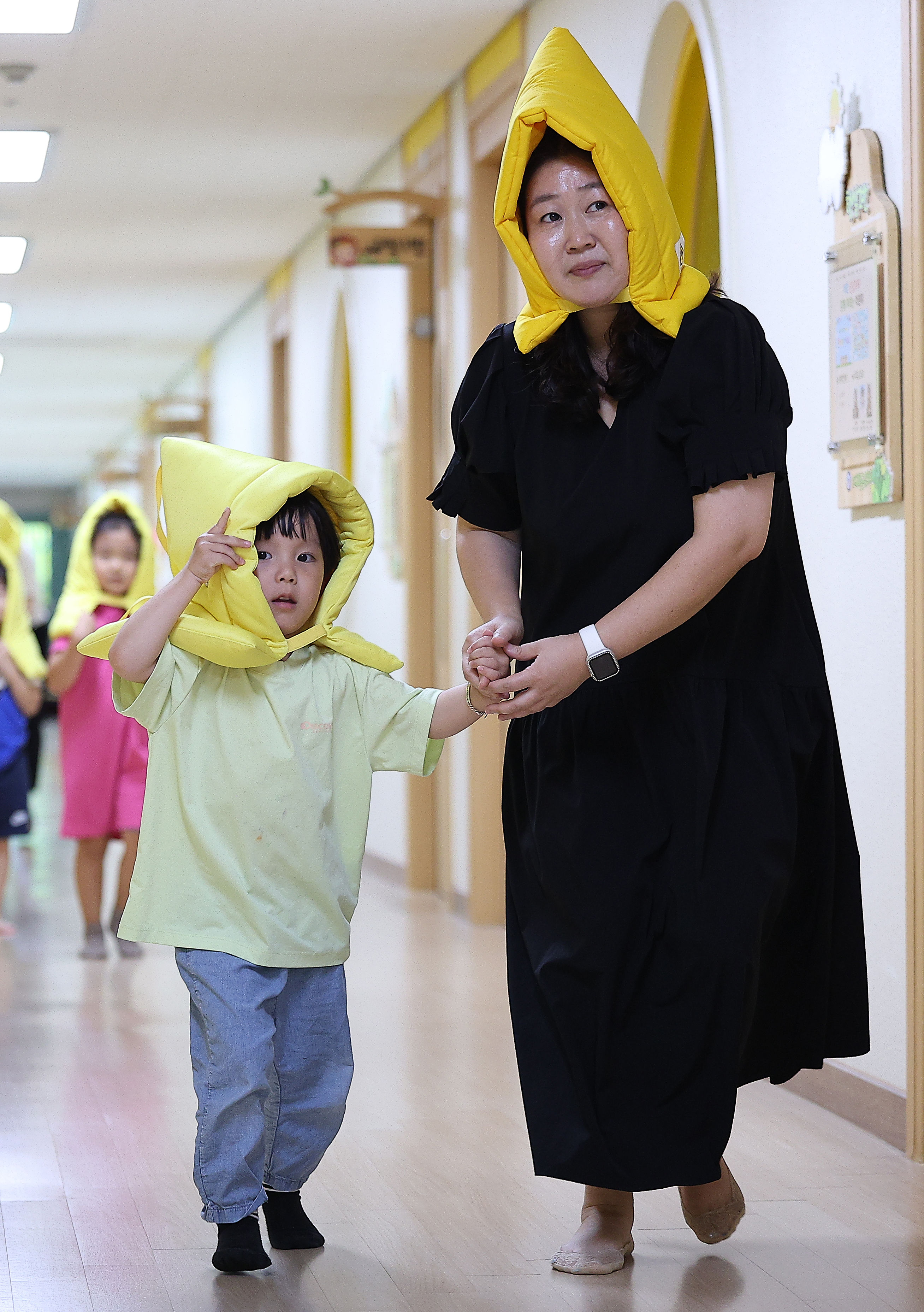 ▲▼南韓實施防空演習，大邱市壽城區黃金幼稚園學童戴著防災冒、緊牽老師的手避難。（圖／達志影像）