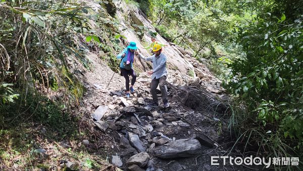 ▲▼警方接獲報案後抵達大鹿林道山壁崩落現場，一邊警戒、一邊協助受困登山客快速將腳踏車抬過落石處。（圖／警方提供）