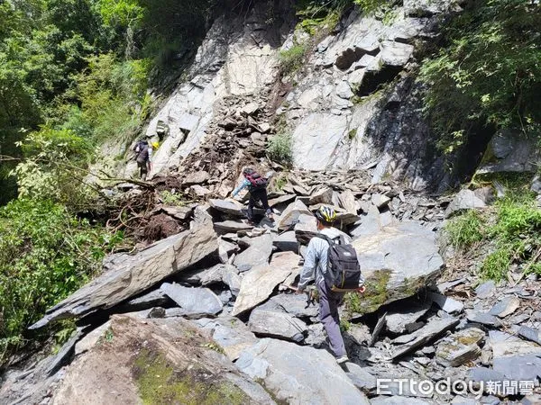 ▲▼警方接獲報案後抵達大鹿林道山壁崩落現場，一邊警戒、一邊協助受困登山客快速將腳踏車抬過落石處。（圖／警方提供）