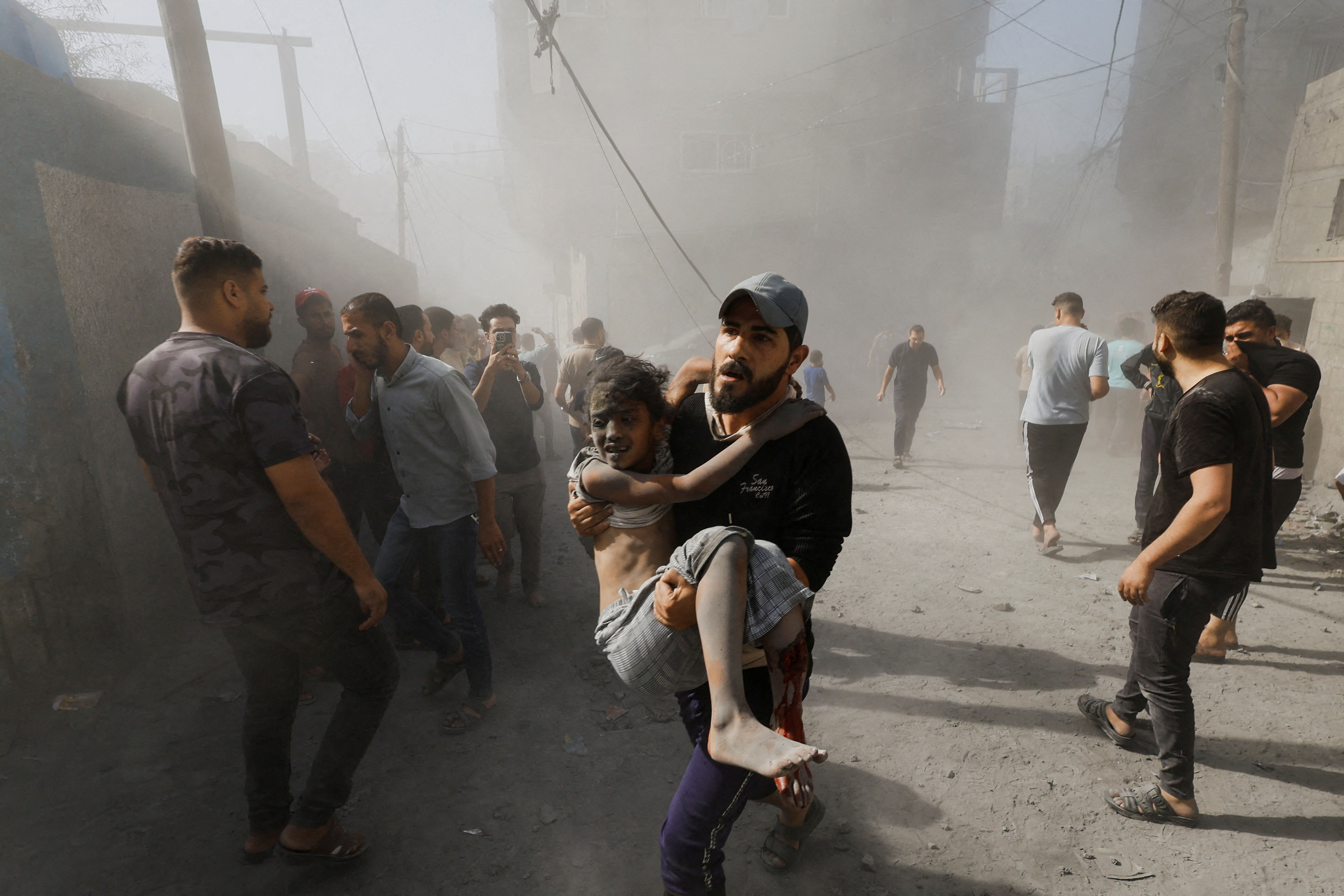 ▲加薩走廊城市汗尤尼斯(Khan Yunis)遭以色列轟炸，男子抱著受傷的小孩逃難。（圖／路透社)