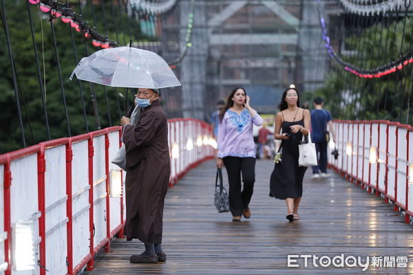 ▲▼受梅雨鋒面逼近的影響，大台北地區在傍晚出現間歇性雨勢，未來幾天不排除有更大與式的可能。圖為遠眺新店文山信義區天氣大景及碧潭吊橋上撐傘化緣的出家人。（圖／記者湯興漢攝）