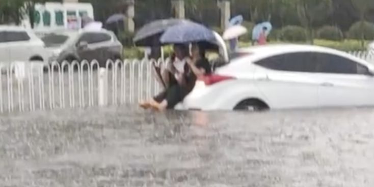 ▲山東臨沂暴雨，有民眾困車輛後行李箱上待援。（圖／翻攝微博）