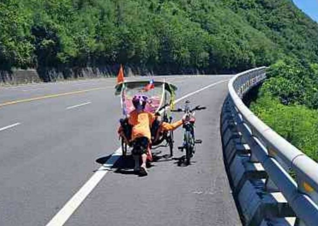 ▲育幼院6歲院童騎不動下車，志工宋明祥協助推腳踏車，而孩子則跑到宋明祥的斜躺車後方幫忙，彼此互推上斜坡。（圖／記者蔡佩旻翻攝）