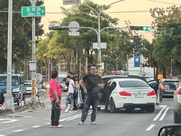 ▲高雄市林園分局警車為了攔車，擋住BMW的去路，一名穿白衣男子被上銬             。（圖／記者吳奕靖攝）