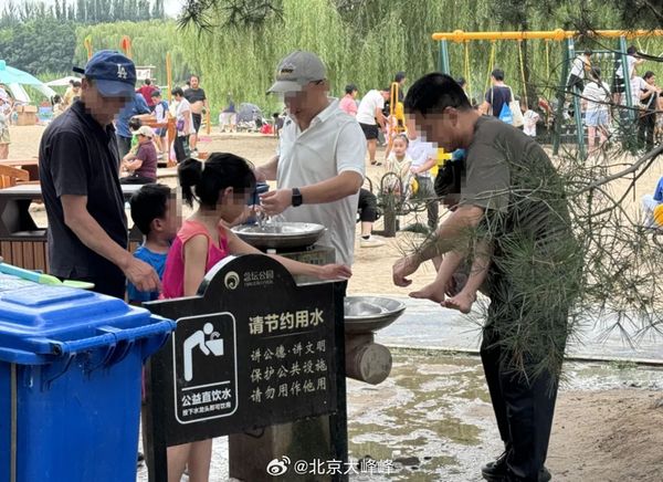 家長濫用北京念壇公園的飲水機，直接抱著小孩幫他洗腳。（翻攝微博）