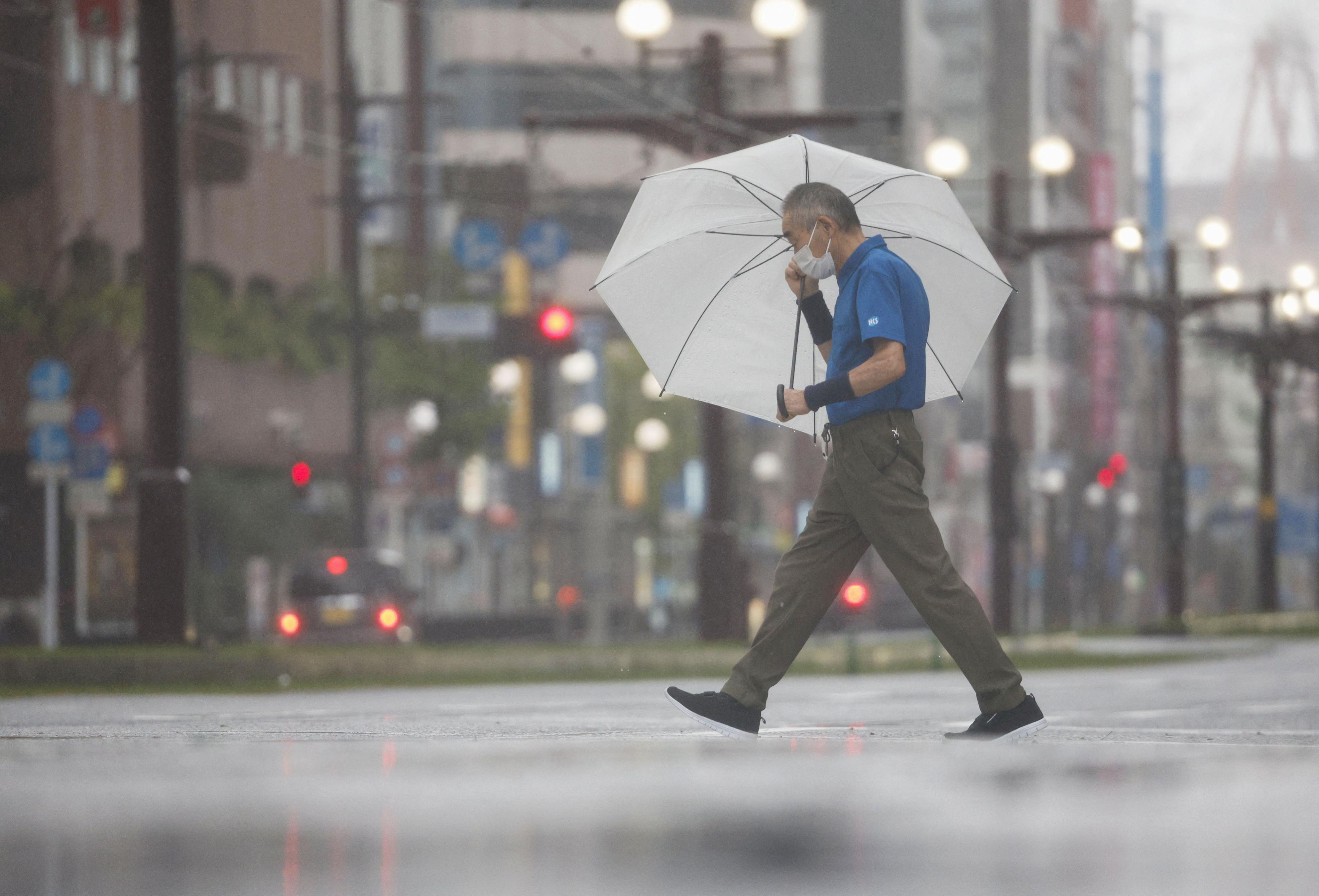 ▲▼颱風珊珊29日上午登陸日本九州，鹿兒島縣路人在道路中撐傘行走。（圖／路透）