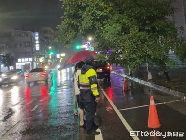 ▲隨著颱風逼近風雨逐漸明顯，台南市中西區南門路中山館前路樹晚上傾斜，造成道路險象環生，二分局警方冒雨警戒查處。（圖／記者林東良翻攝，下同）