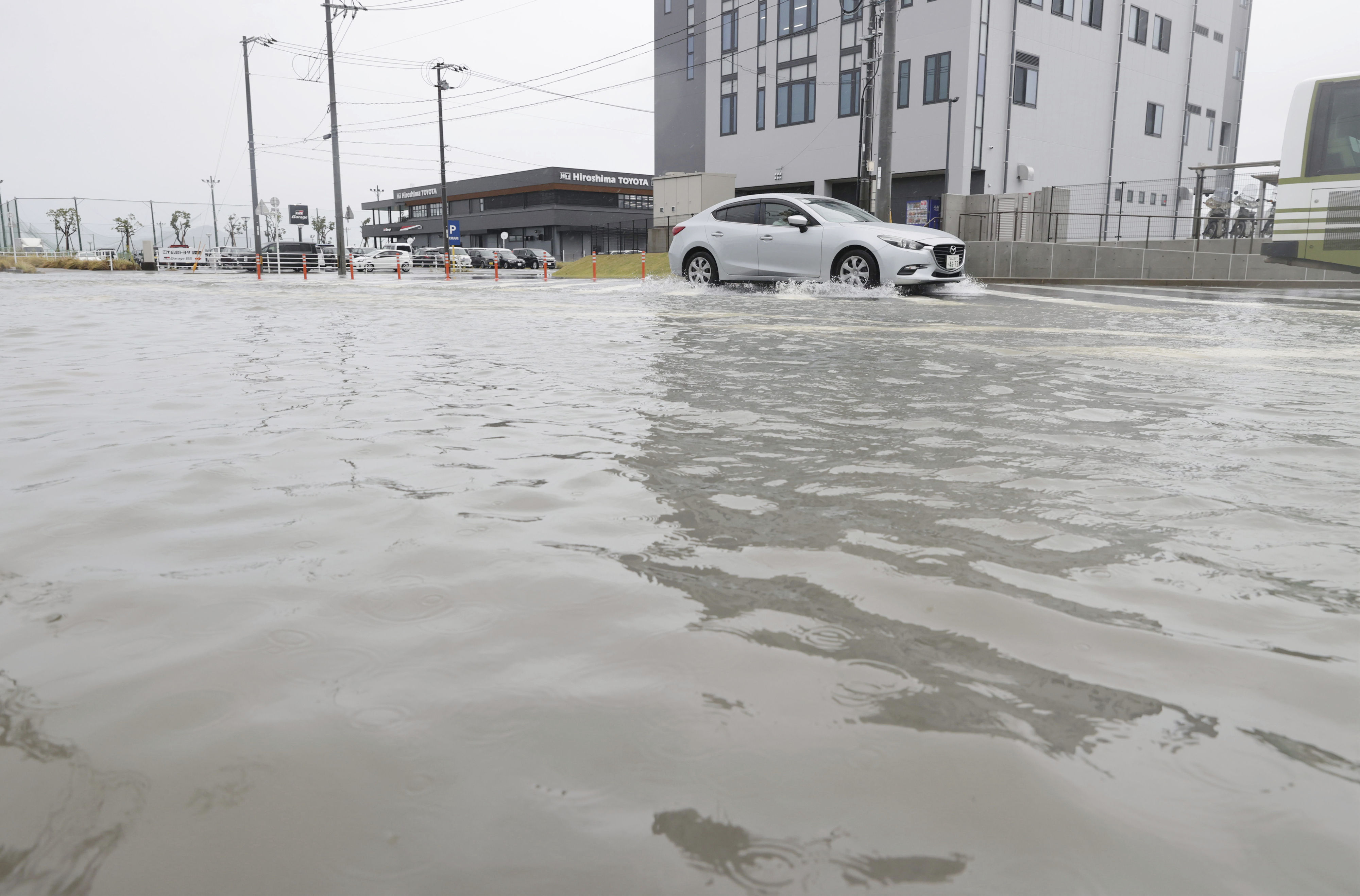 ▲▼低氣壓與鋒面2日造成西日本降下暴雨，廣島縣廣島市一輛汽車行駛於被洪水淹沒的道路。（圖／達志影像／美聯社）