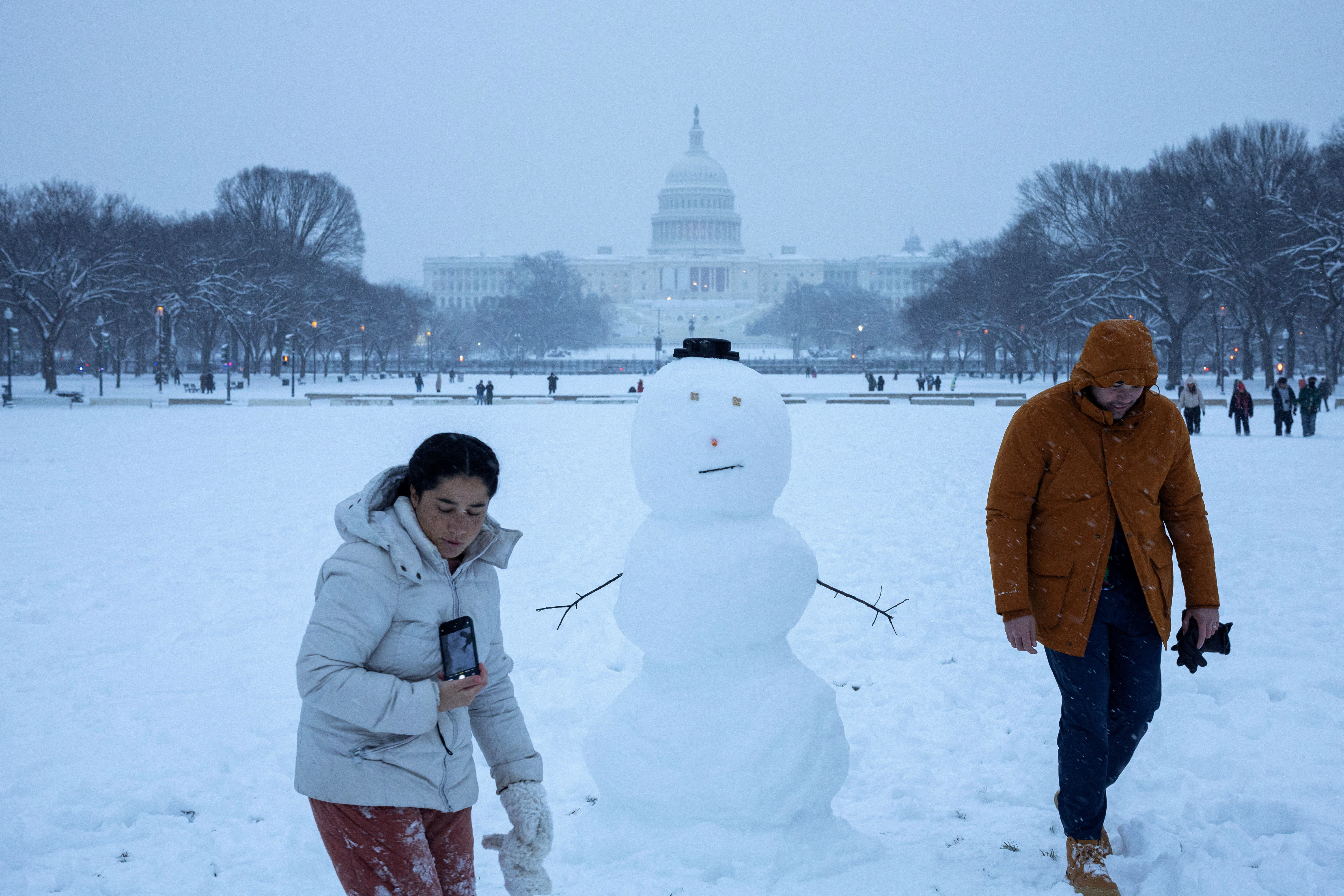 ▲▼美國東部降下暴雪，民眾在華府國會大廈前的雪人旁行走。（圖／路透）