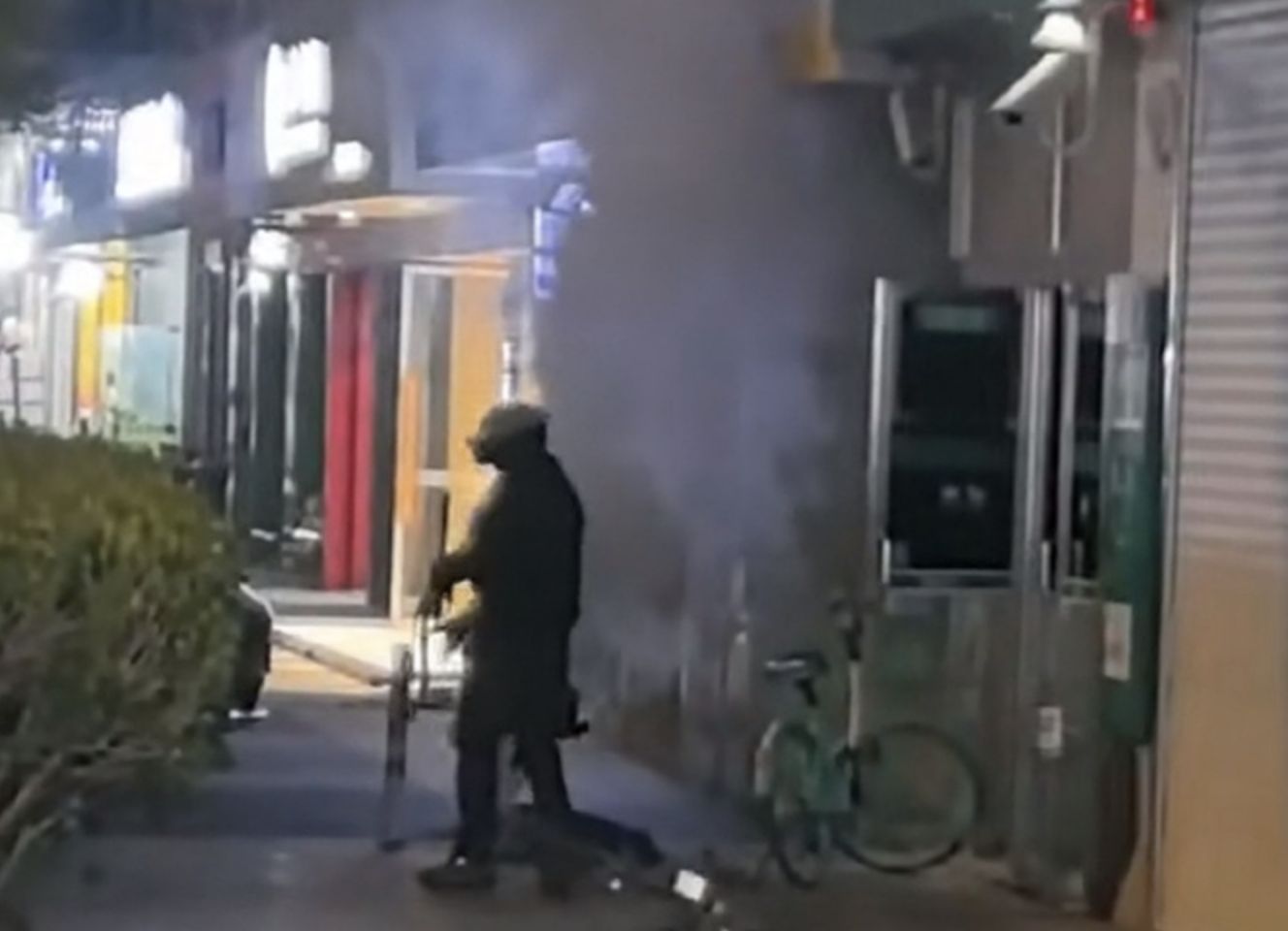▲上海一名疑似患有精神疾病的男子在夜間持CS遊戲煙霧罐朝ATM提管機丟擲。（圖／翻攝微博）