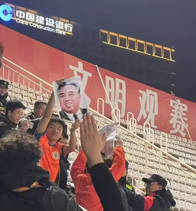 ▲▼中國球迷在觀眾席亮出金日成的相片,事後被當地保安發現,要求丟垃圾桶。(圖/翻攝自X)