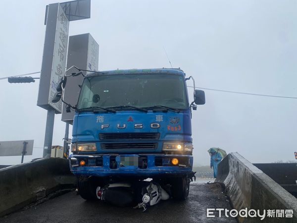 ▲載運飼料大貨車轉彎進支線道路時，機車衝撞貨車後鑽進車底，騎士大腿骨折送醫。（圖／記者楊永盛翻攝）