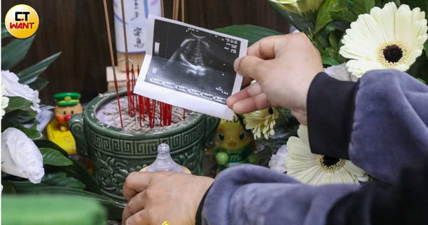 黃女拿著先前在診所做過產檢的超音波照與來不及給兒子喝到的奶粉和奶瓶，在靈堂前祭拜。（圖／黃耀徵攝）