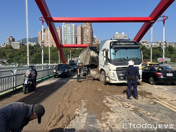 ▲▼關渡橋砂石車後斗泥漿滲落車道，交警協助清理路面             。（圖／記者陳以昇翻攝）