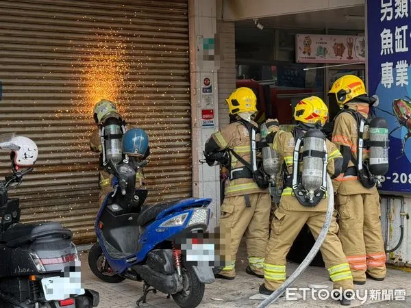 ▲台南市東區東門路二段1處1層鐵皮商店，31日上午10時12分許發生火警，1樓處有濃煙竄出，消防人員破壞鐵捲門接駁水線延伸進火場全力射水搶救。（圖／記者林東良翻攝，下同）