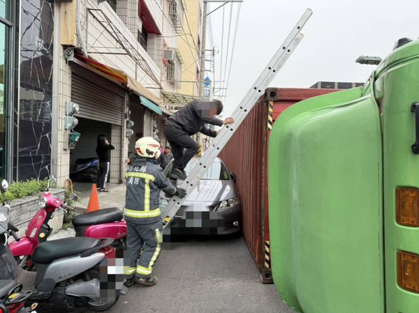 ▲聯結車左轉失控翻覆駕駛自行爬出由消防員協助爬下雙截梯。（圖／民眾提供）