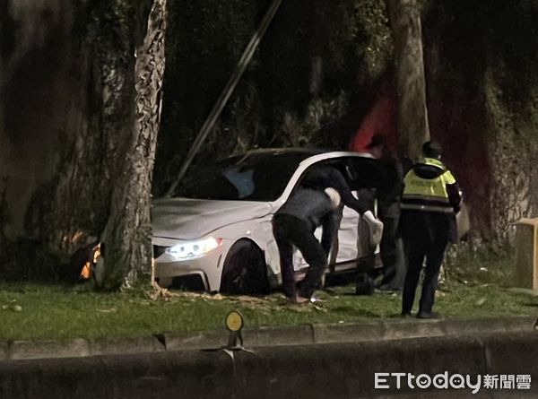 ▲▼北市中山區樂群一路有1台BMW轎車，衝進路邊草皮卡在防波圍牆、樹木中間。（圖／記者讀者提供）