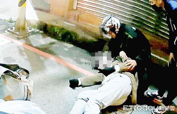 ▲桃園市陳姓騎士昨晚騎車經過桃園區中正路、慈祥街口處停等紅燈時，突然倒臥地上，路過騎士與巡邏警幫忙扶至路旁查看。（圖／記者沈繼昌翻攝）